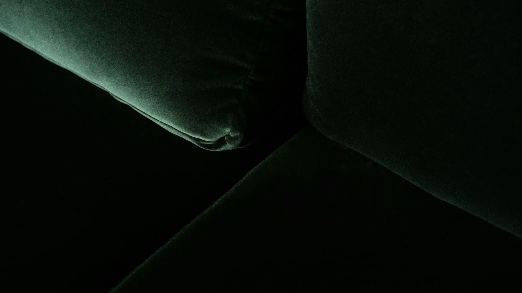 Detail of a deep green velvet sofa in soft light