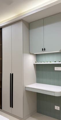 Full-height wardrobe beside a study desk with sage fluted panelling
