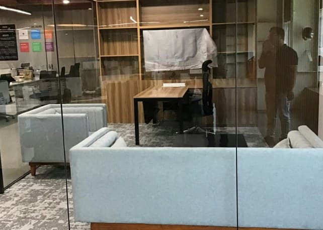 Glass-walled executive cabin with timber shelving and lounge sofa