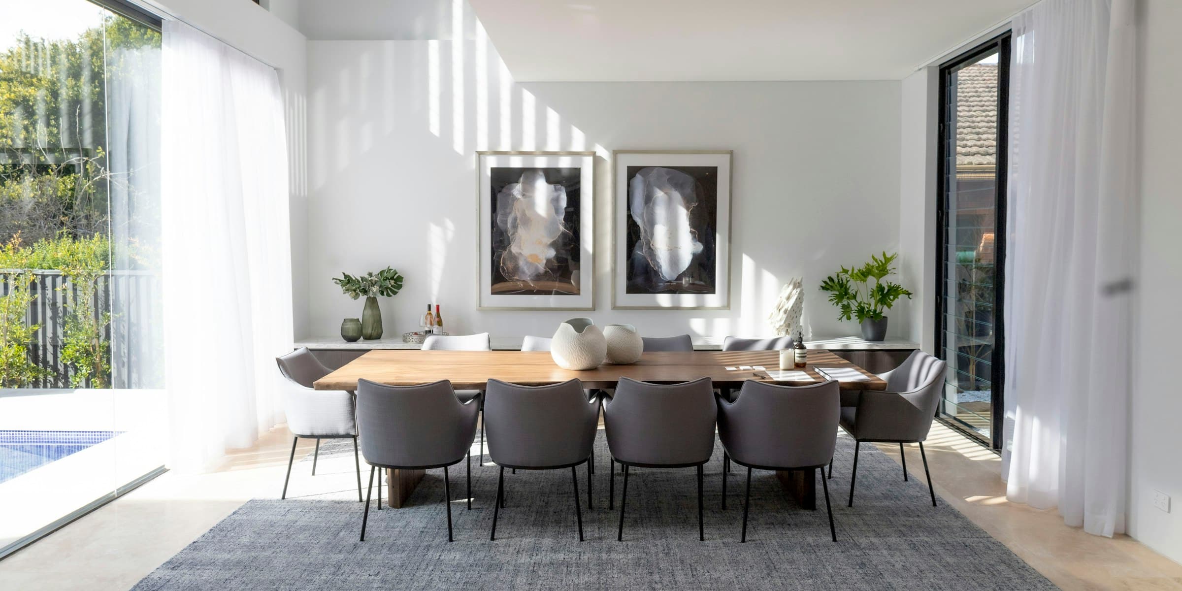Refined dining room with long table, upholstered chairs and framed artwork