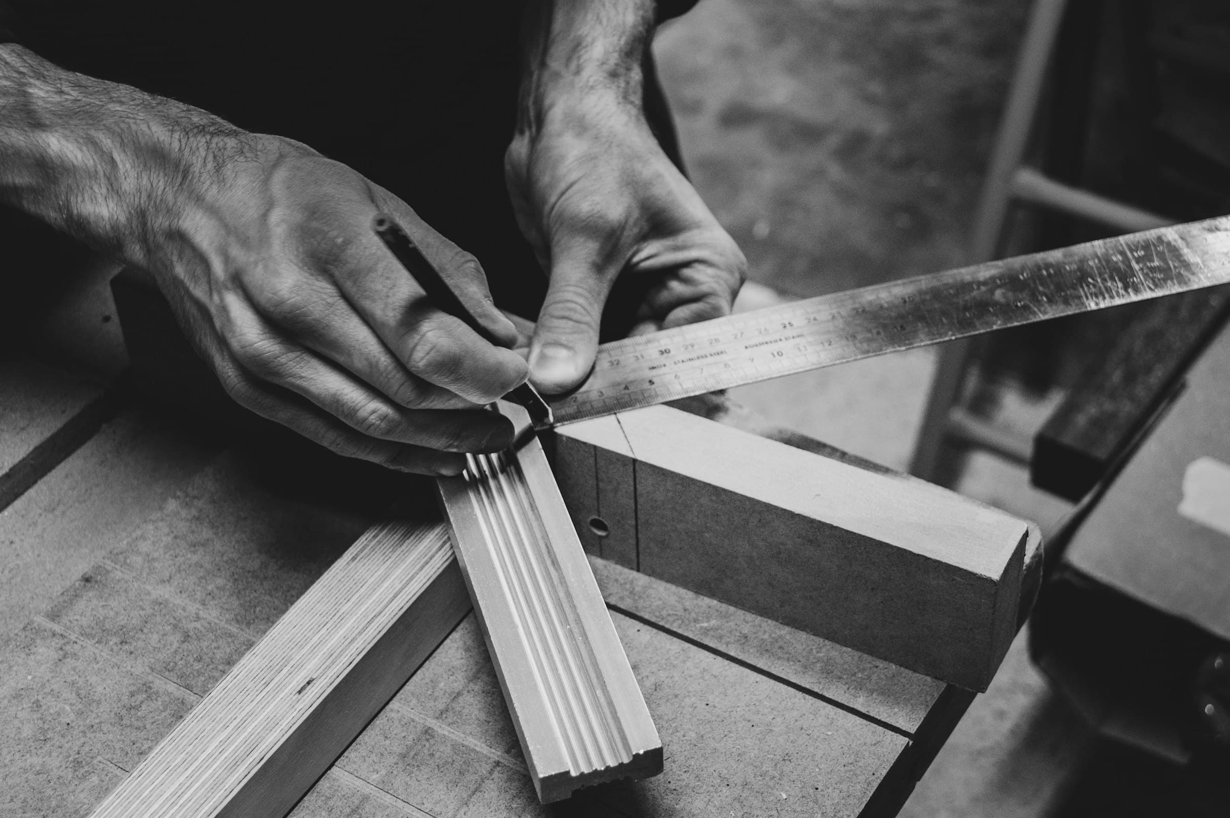 Craftsman's hands measuring a timber joint with a steel rule